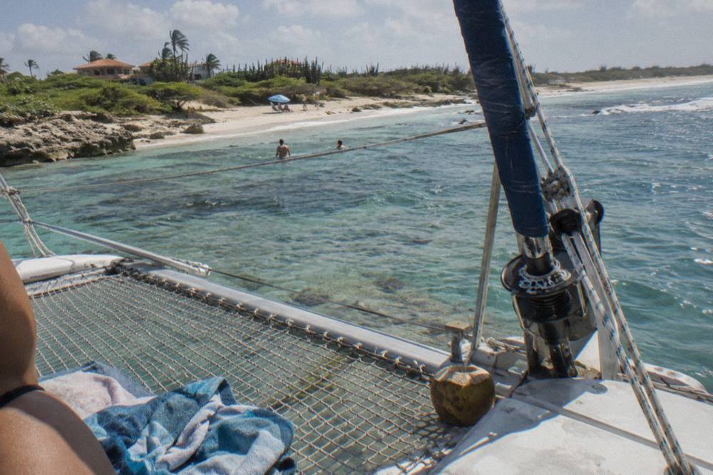 A catamaran deck with nets and seating over clear shallow water