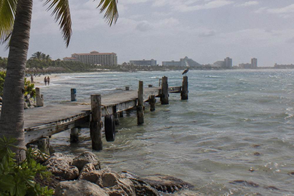 A wooden pier extending into calm Caribbean water at morning