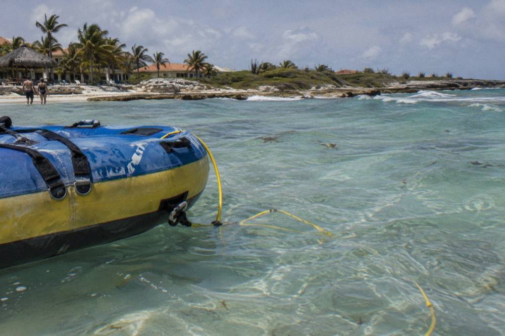 A raft floating on calm water above a pale sandy bottom with light rays