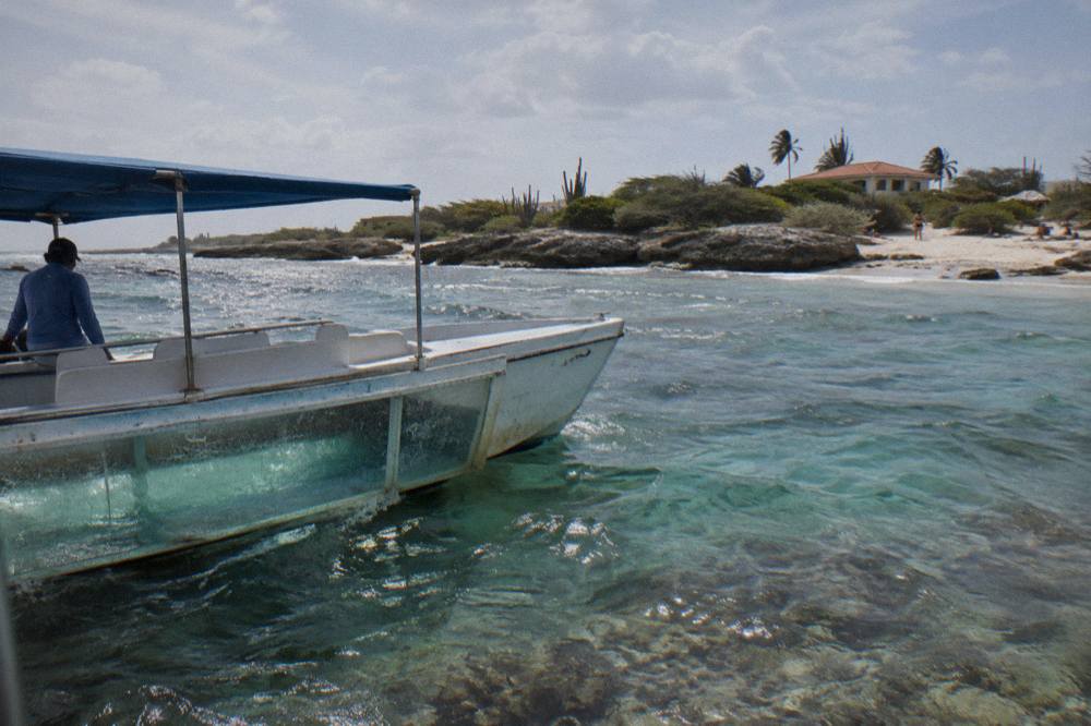A glass bottom boat drifting over a shallow reef in turquoise water