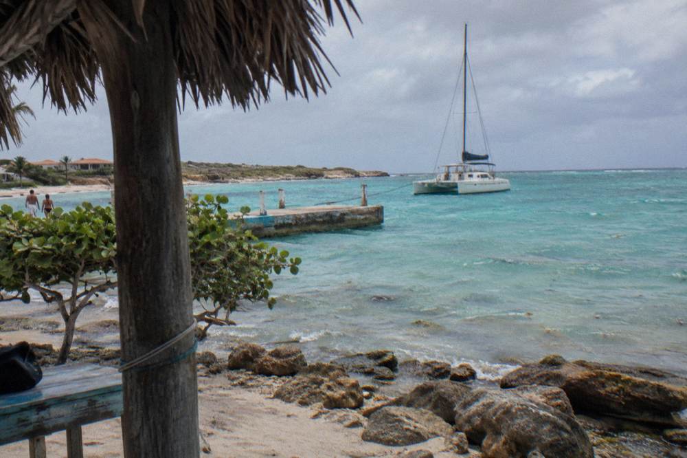 A catamaran anchored in calm turquoise water near a beach pier