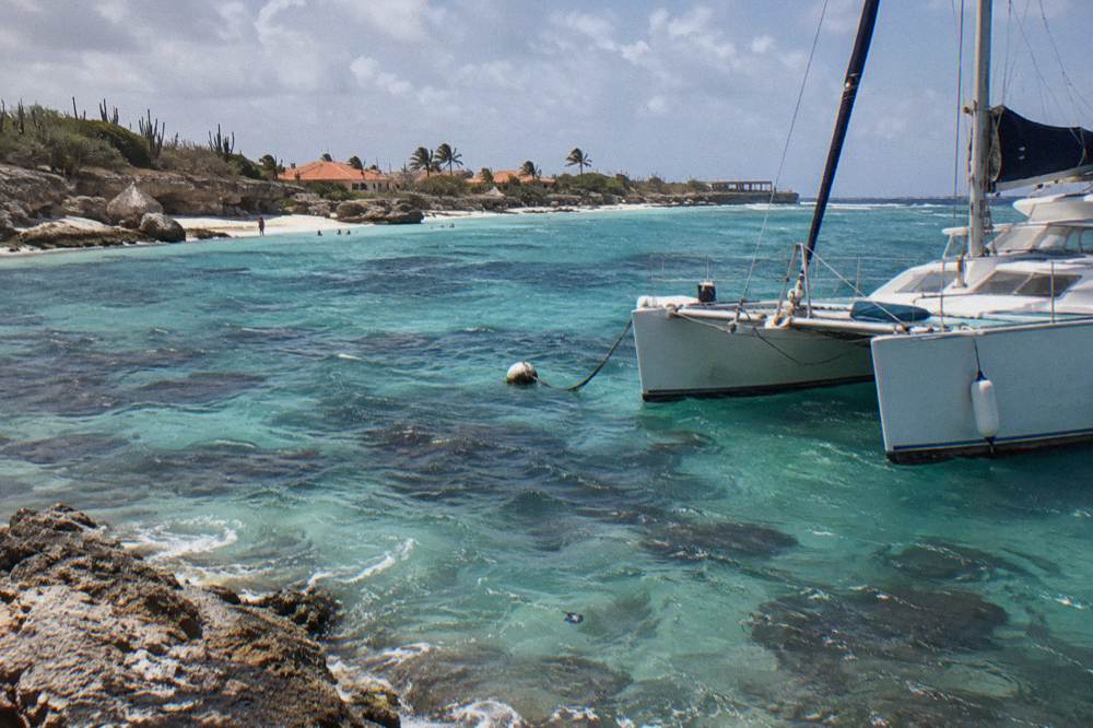 A catamaran anchored in clear shallow water near a reef