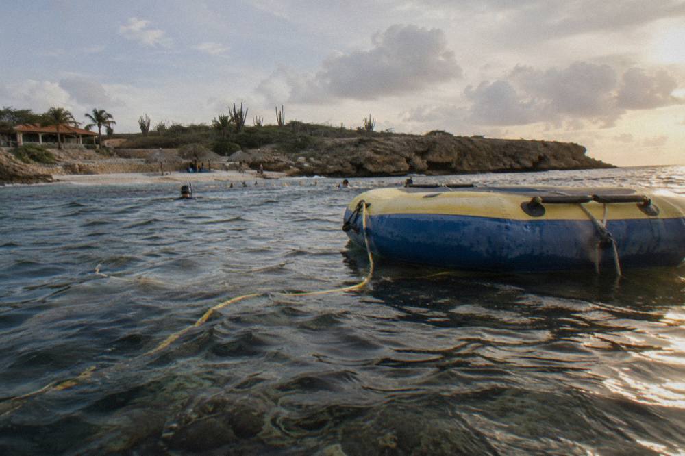 A floating raft with an air hose resting on still blue water near a reef