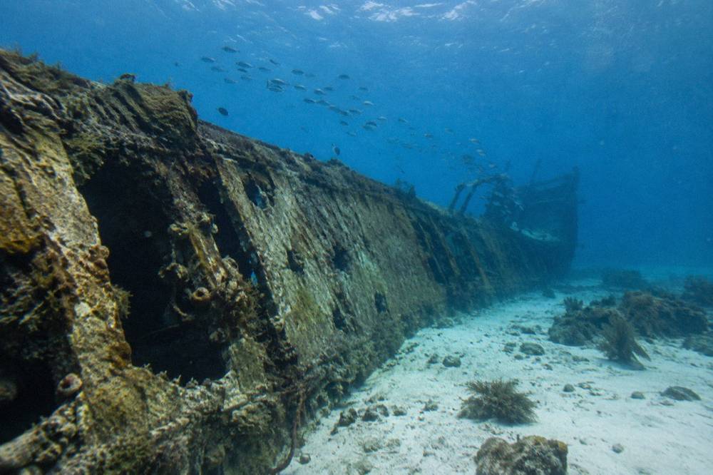 Hull of a sunken ship lying on its side underwater in blue sea