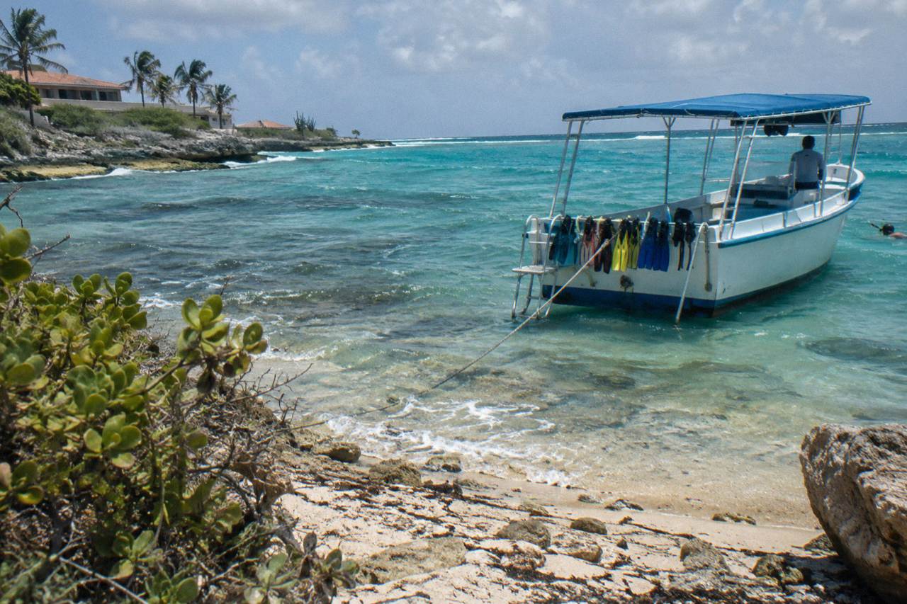 A snorkel boat moored over a shallow reef in clear turquoise water near the Aruban coast