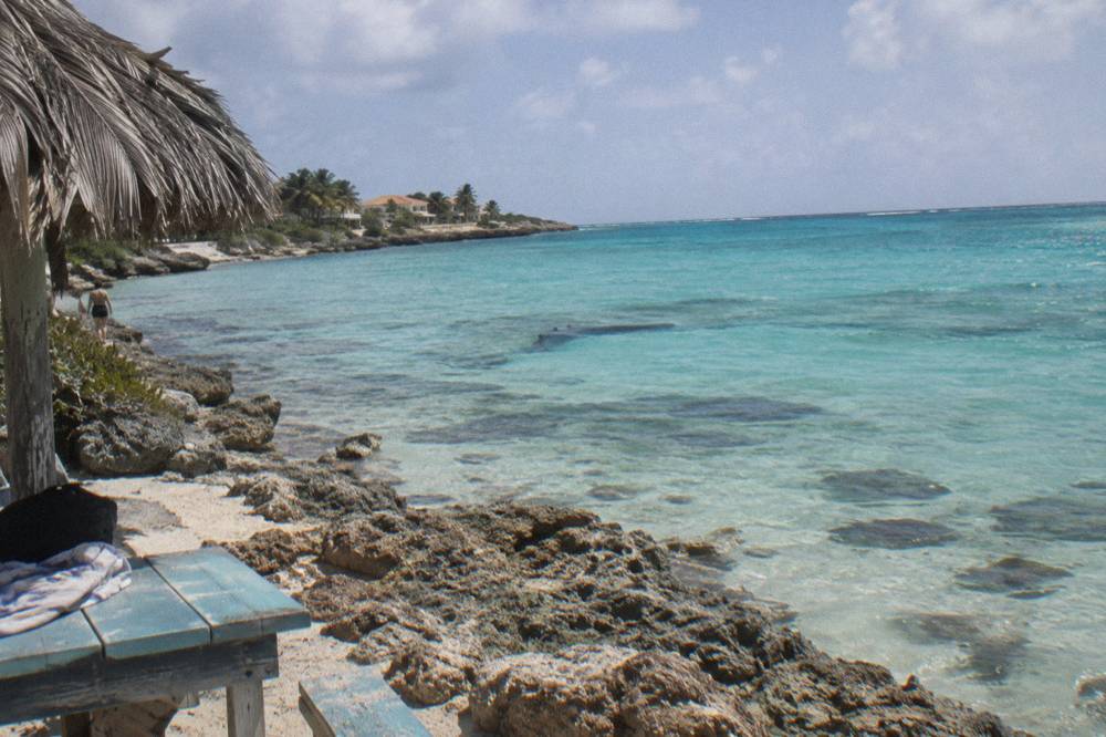 Calm turquoise sea above a shallow reef with the dark outline of a sunken hull in the distance