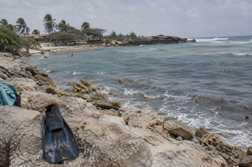 A small rocky bay with clear water over a nearshore reef and gentle waves