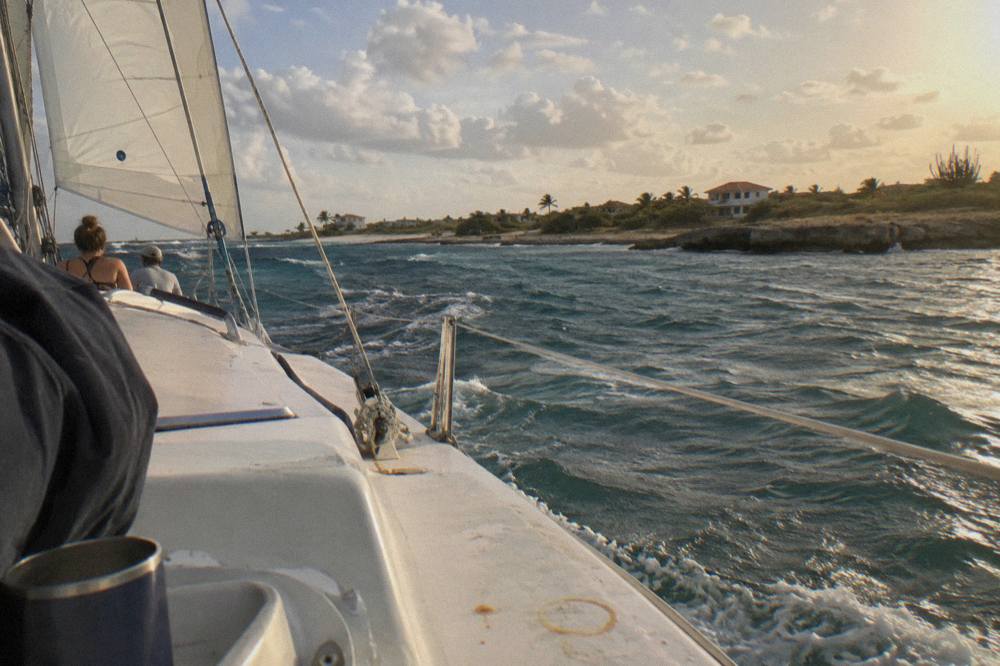 A catamaran under sail along a calm Caribbean coastline