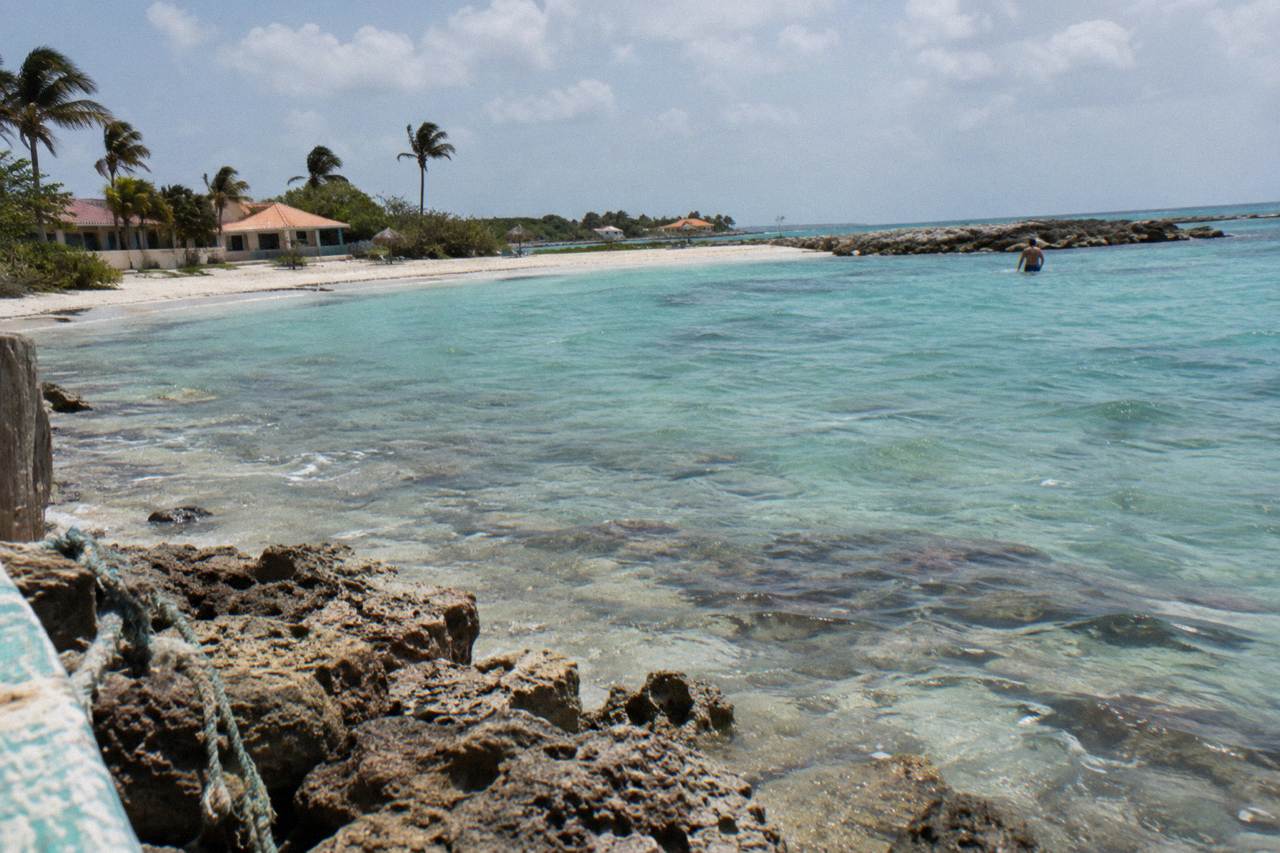 Calm turquoise water over a shallow coral reef close to a sandy beach
