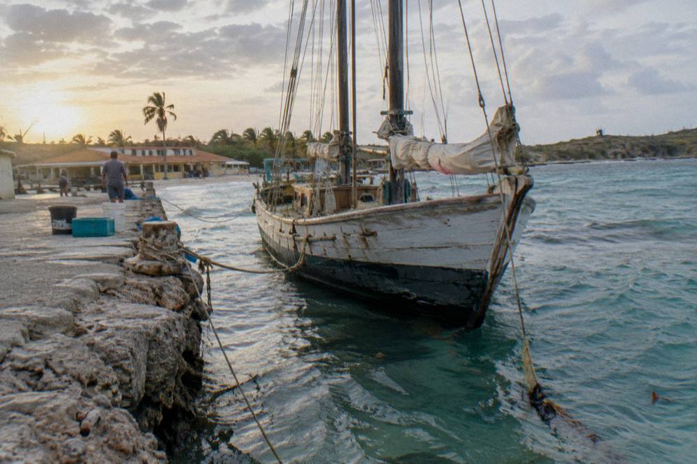 A wooden schooner with masts moored at a pier in morning light