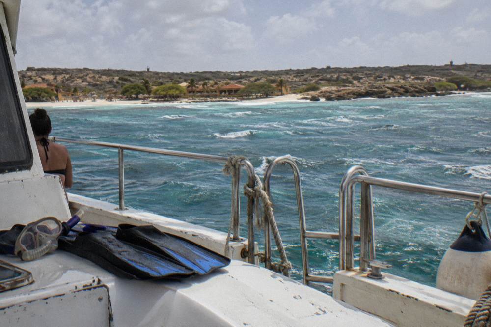 Snorkel fins and mask resting on a boat deck above calm sea