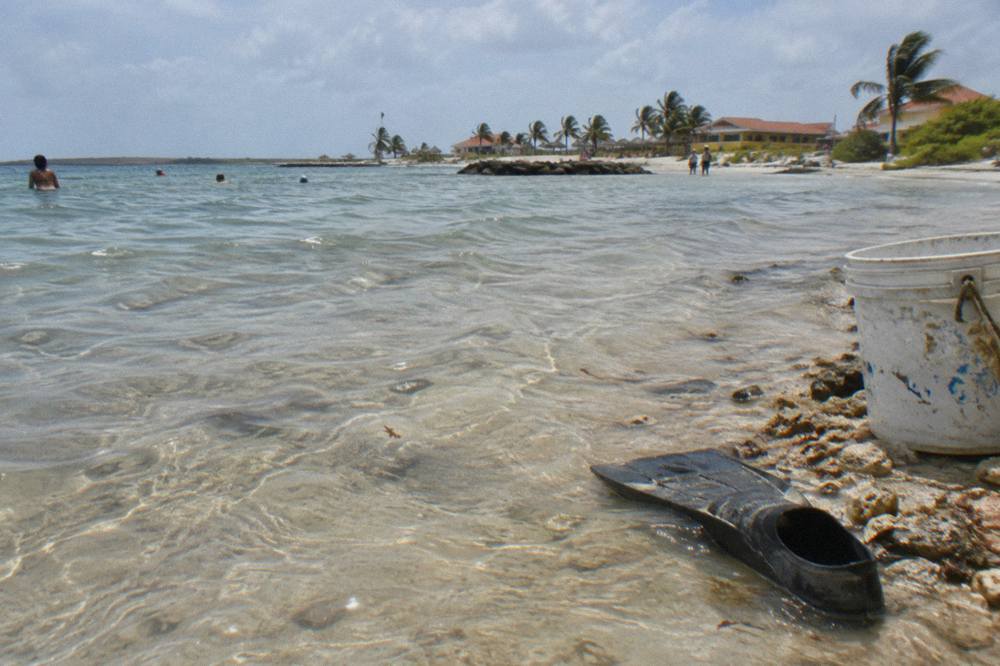 Shallow clear lagoon water over pale sand at Baby Beach with gentle ripples on the surface