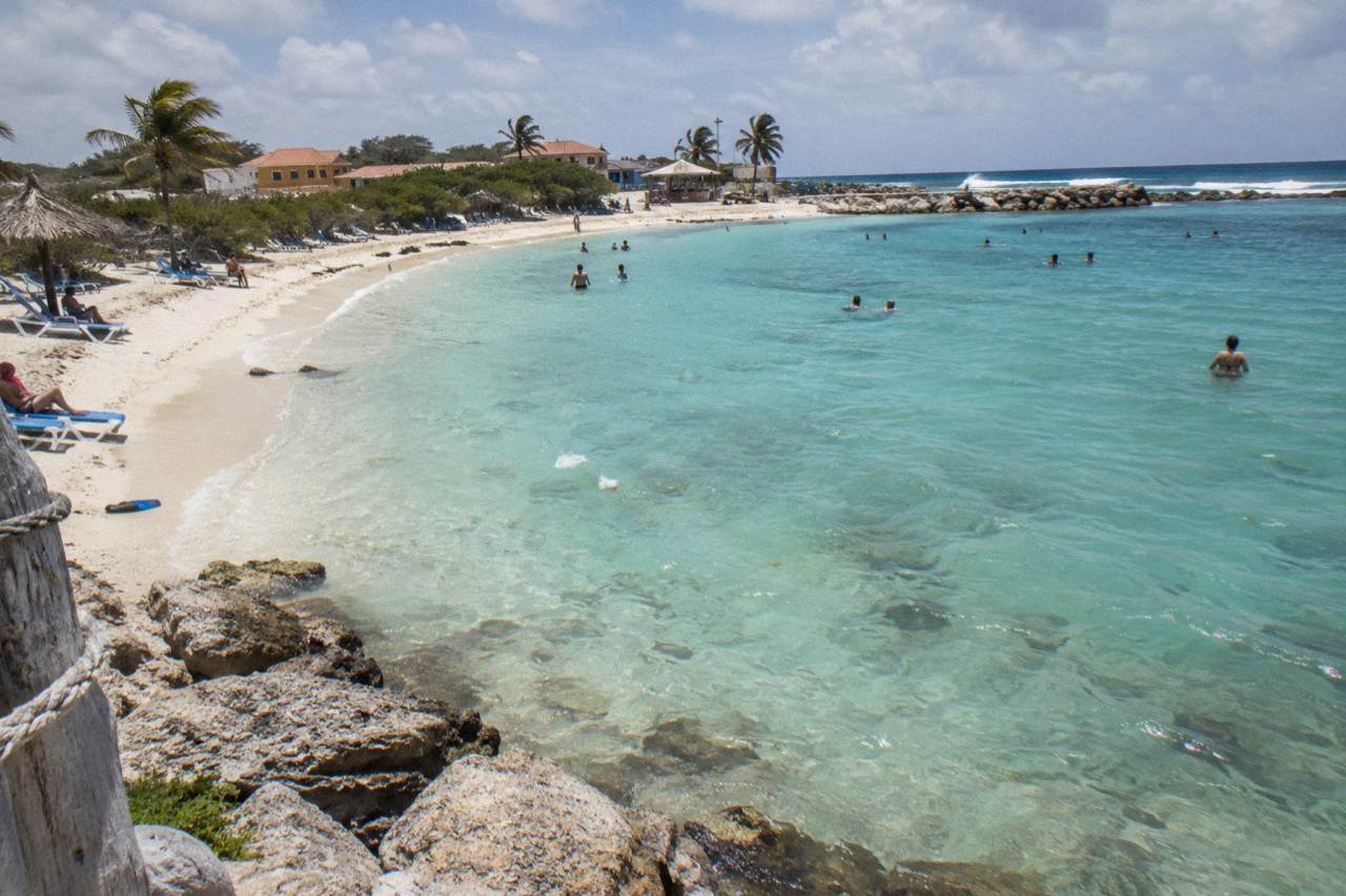 Calm shallow turquoise lagoon water at Baby Beach with a sandy bottom and clear sky