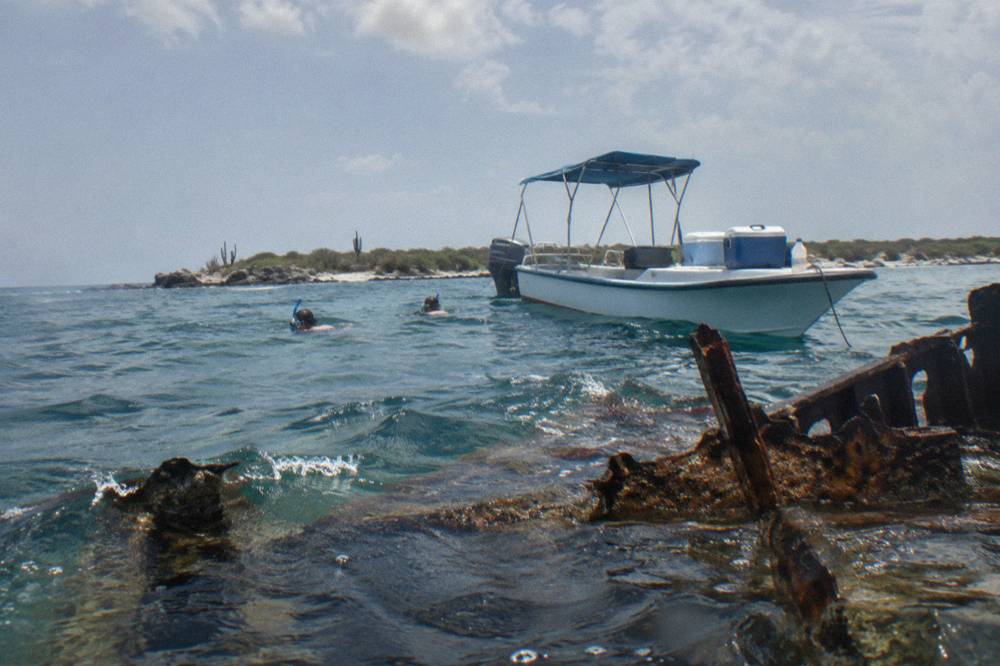 A snorkel boat anchored near a reef with guests in the water beside it