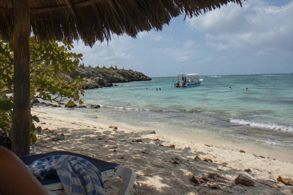 Snorkel boat anchored over clear shallow water near a rocky shoreline