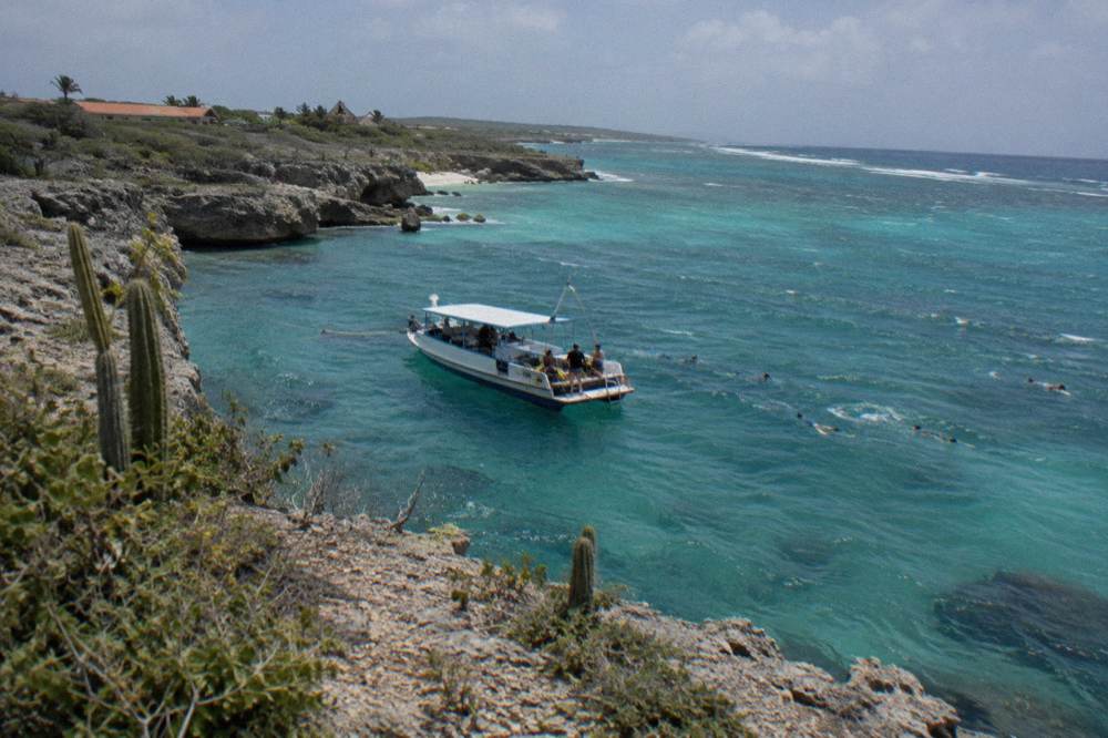 Snorkel boat anchored near a rocky coastline with calm turquoise water