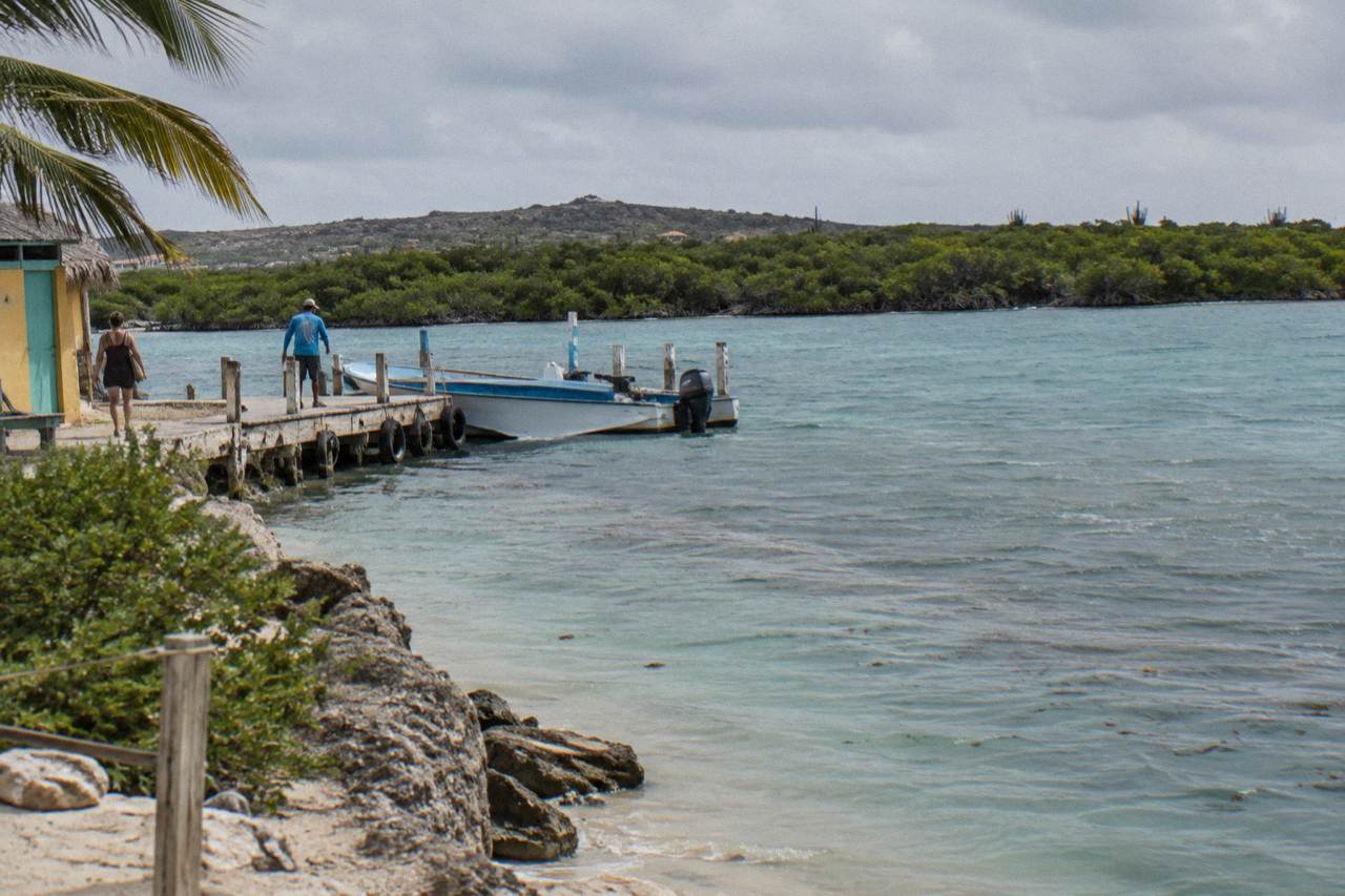 Calm turquoise water around a small Caribbean island with a wooden ferry dock