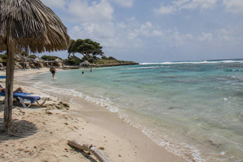 A sunlit Caribbean beach with gentle waves and clear shallows along the shore