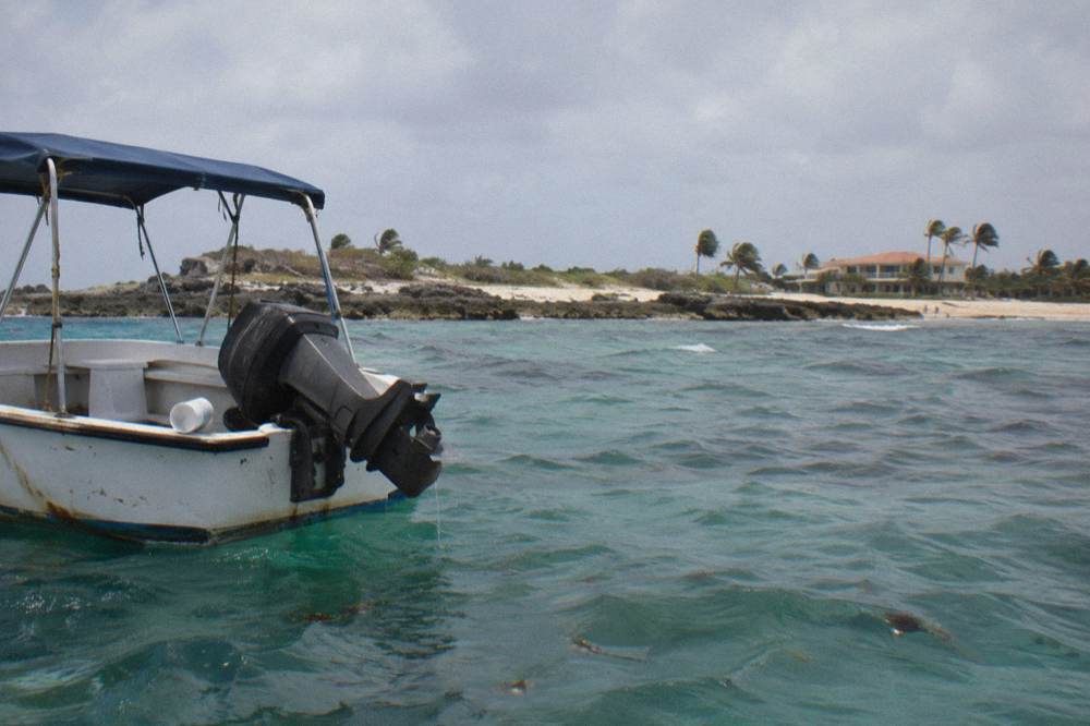 A small boat with a bimini shade roof drifting over clear water near a reef