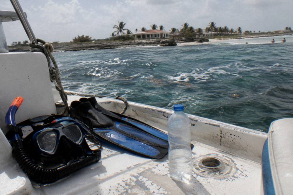 Snorkel fins and a mask resting on a boat deck beside a water bottle