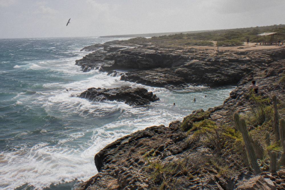 A rocky desert trail in a national park leading toward a distant turquoise coastline