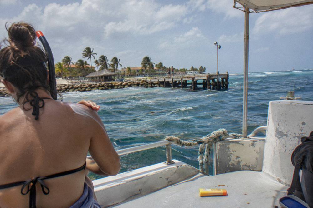 Snorkeler applying sunscreen on the deck of a boat near palm trees