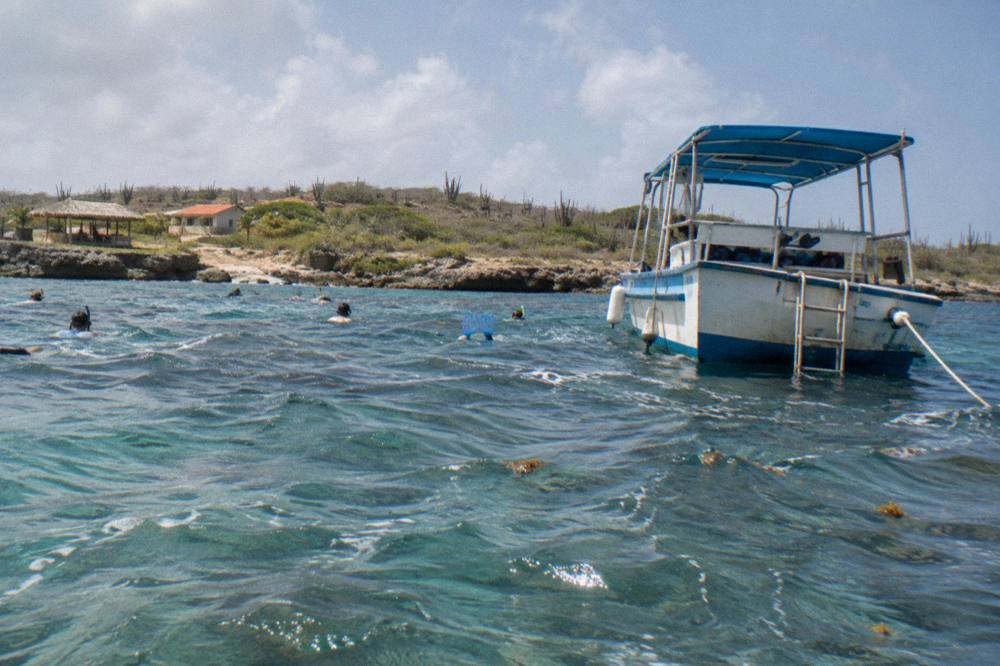 Snorkel boat anchored near a reef with passengers in the water beside it