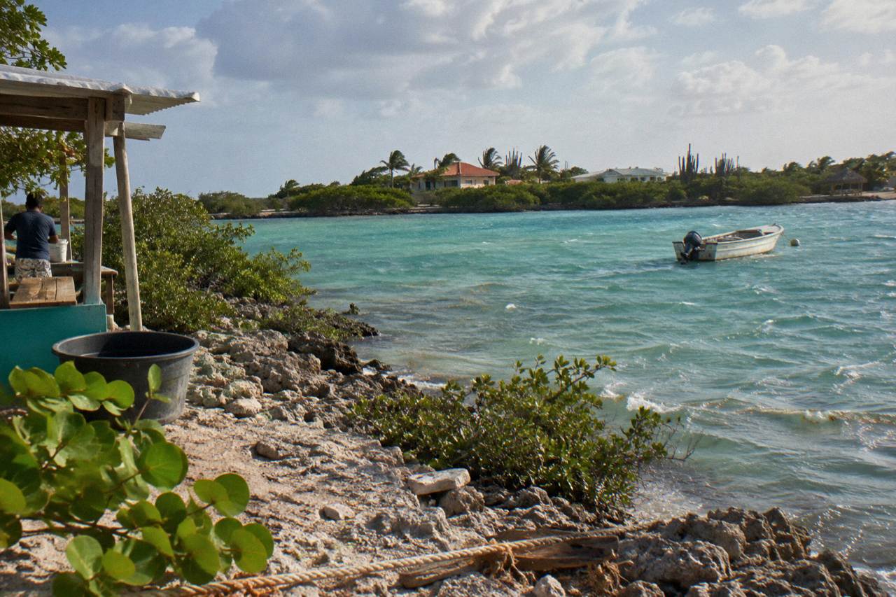 Calm turquoise water along a rocky shoreline with a small boat anchored offshore