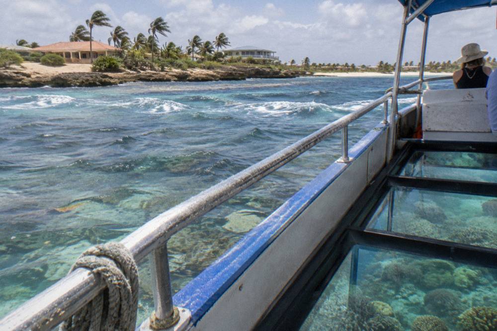 A small glass bottom boat drifting over a shallow reef close to shore