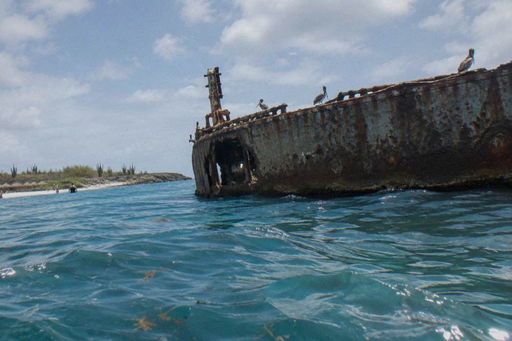 A shipwreck hull breaking the surface of calm blue water