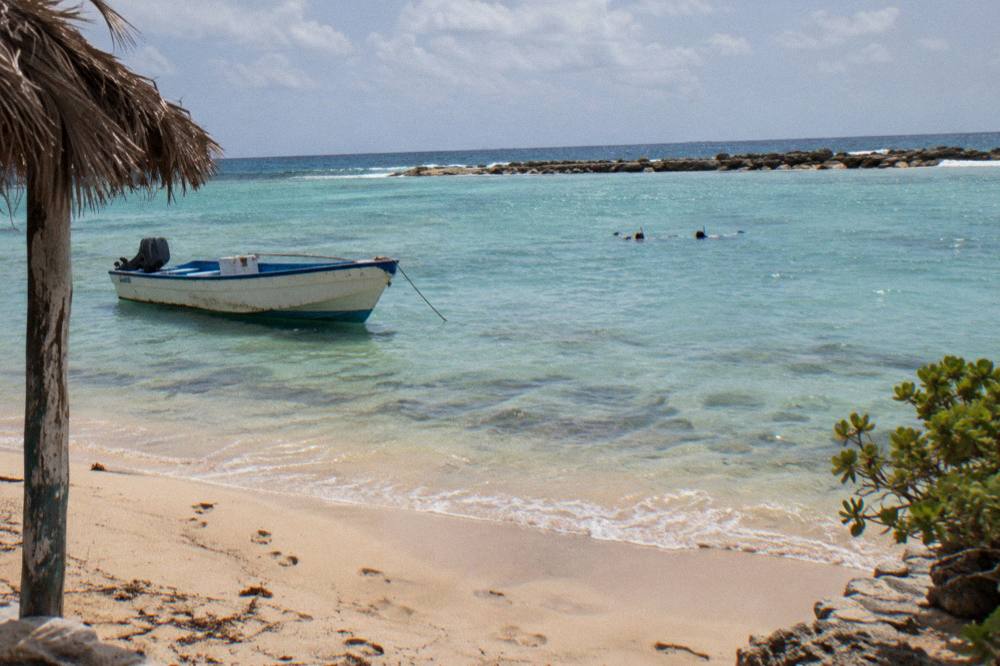 A small boat anchored over clear water with snorkelers nearby