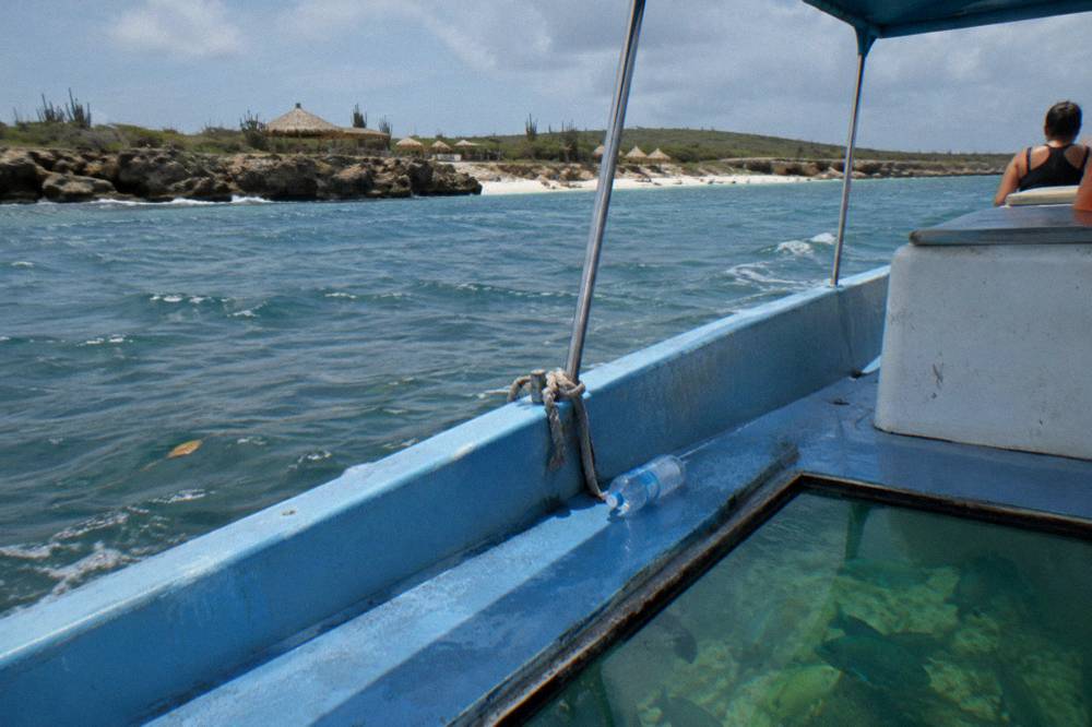 A small boat with a glass viewing panel drifting over a coral reef in clear water