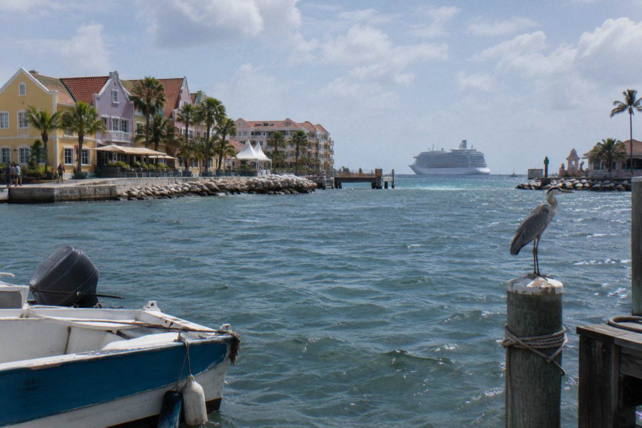 A cruise ship at anchor beyond a calm Caribbean bay with clear turquoise water