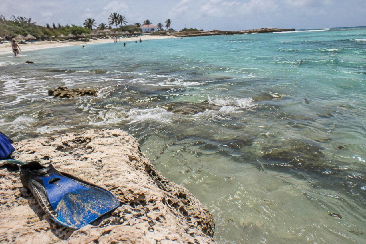 Calm turquoise water over a shallow reef close to a sandy beach