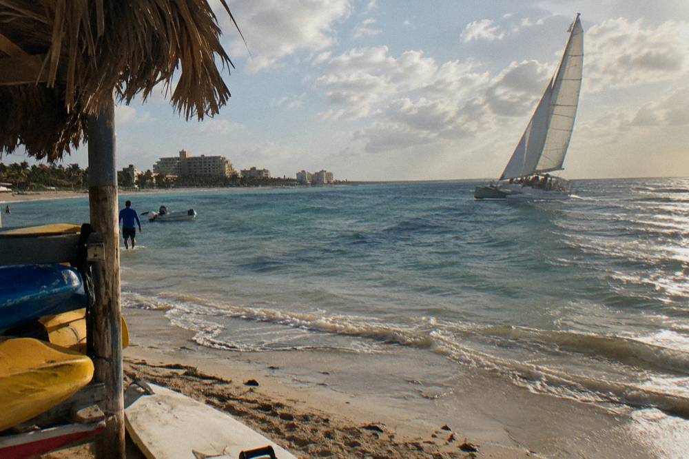 A catamaran under sail on calm blue water in late afternoon light