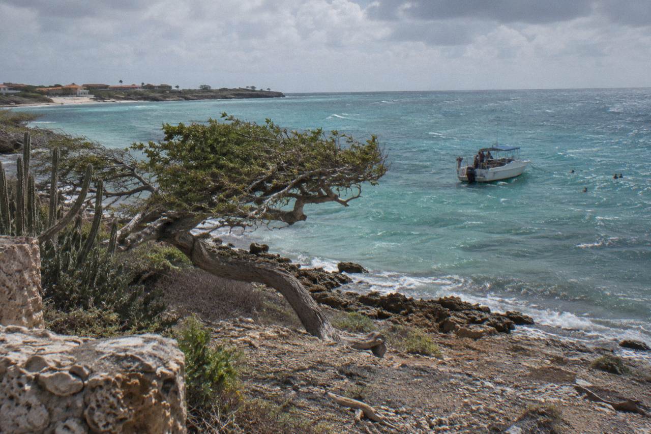 Calm turquoise water along a protected Aruba beach with a snorkel boat moored offshore