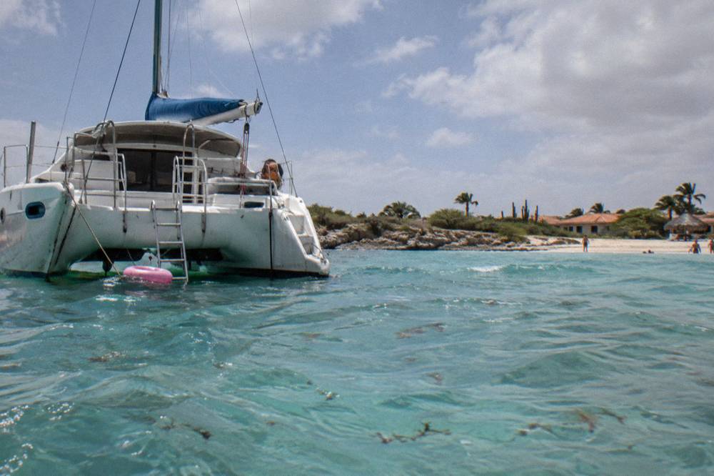 A catamaran anchored in calm shallow water near a coral reef