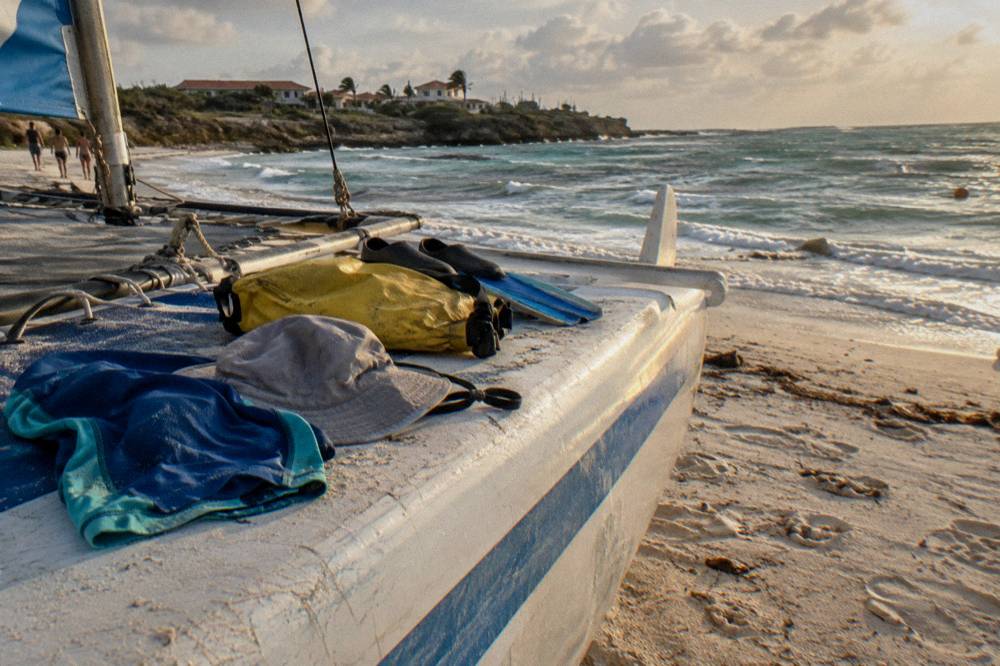A rash guard, hat and dry bag arranged on a boat bench beside snorkel fins