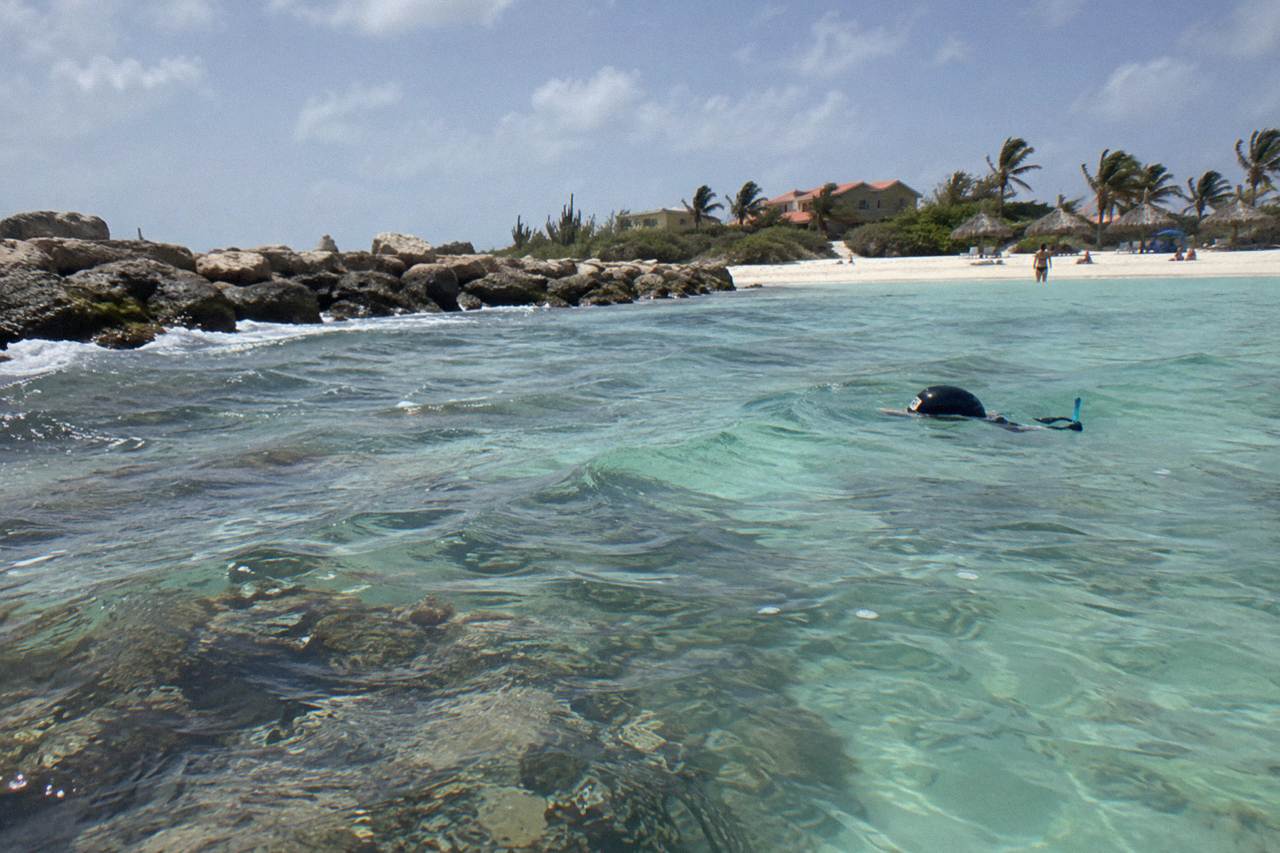 Calm turquoise shallows over a coral reef close to a white sand beach